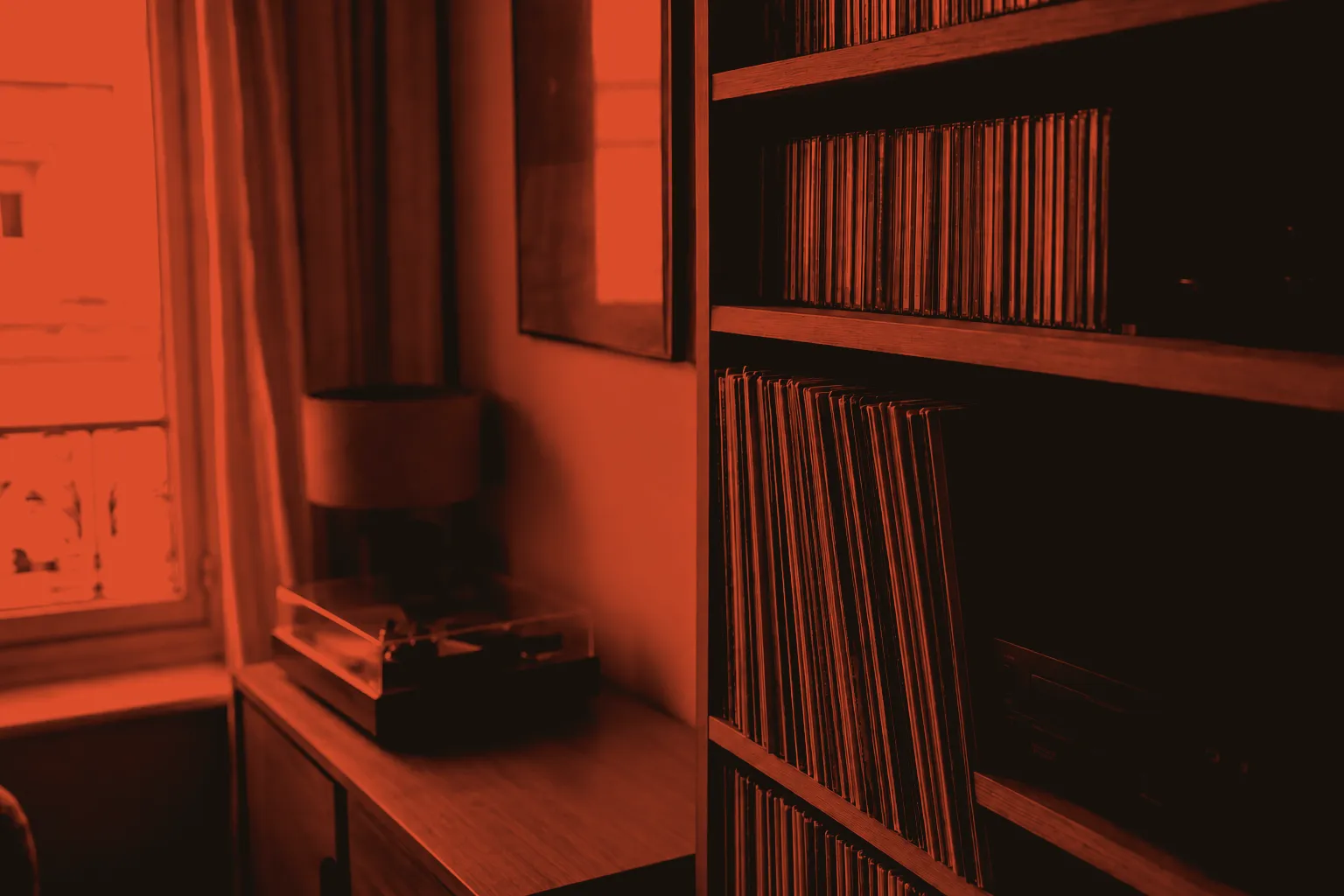 A home music collection with vinyl records and CDs on wooden shelves beside a window.