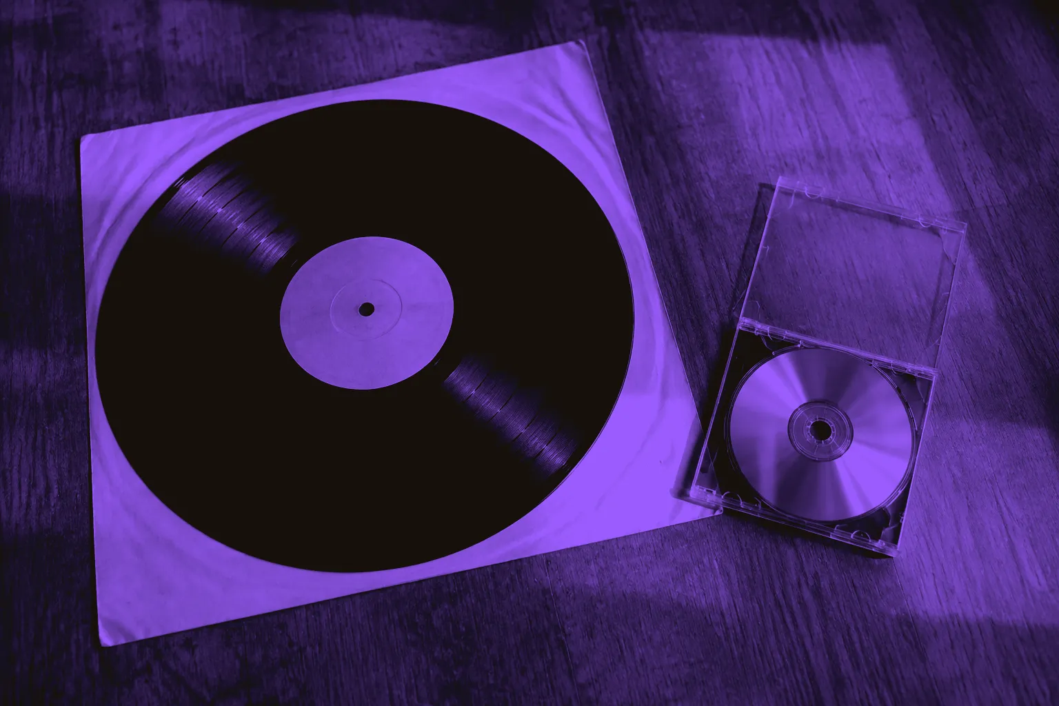 A vinyl record and a compact disc beside their sleeves and cases.